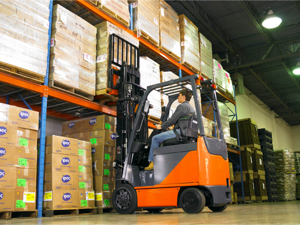 A Toyota forklift operator unloading a heavy load inside a warehouse.